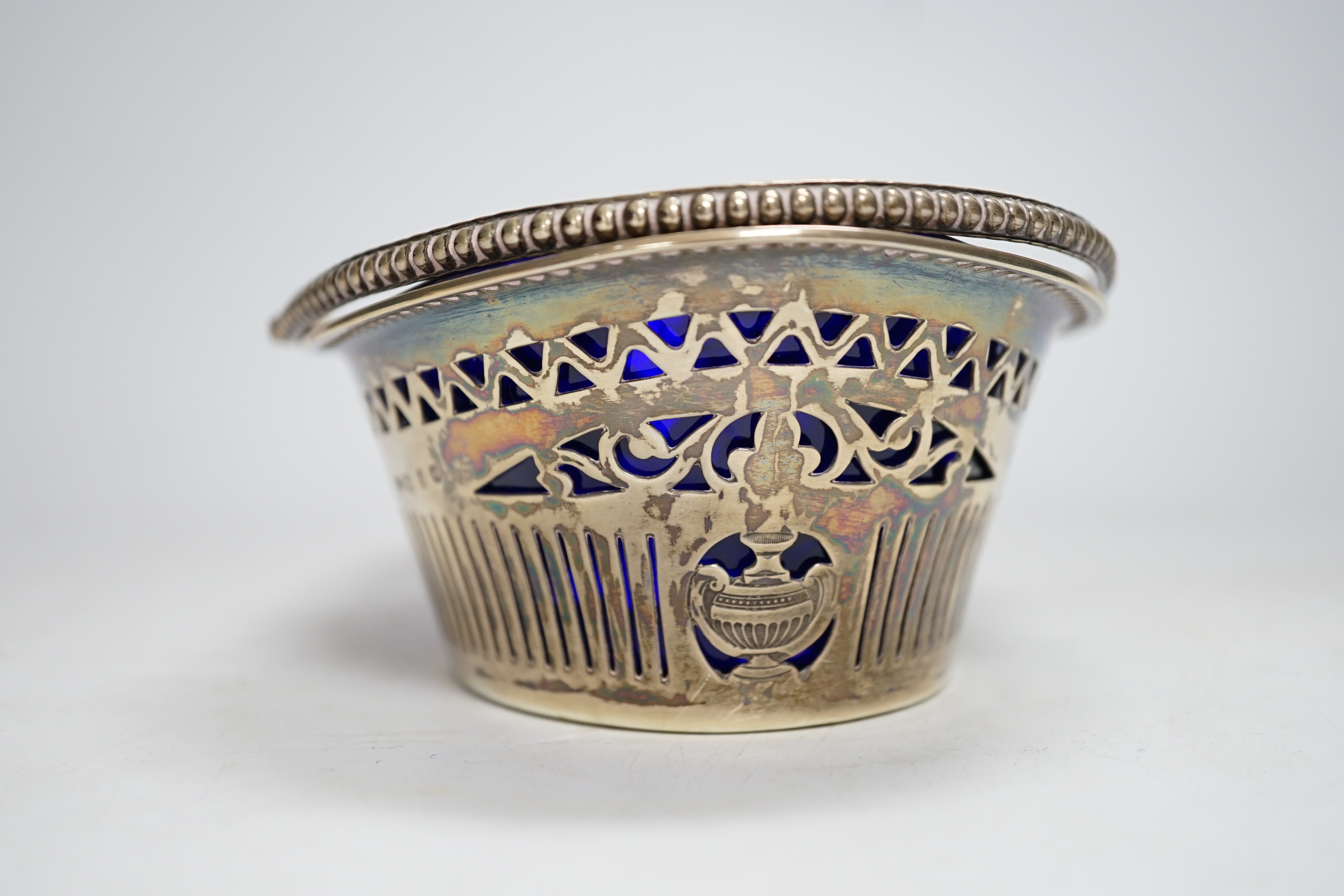 A late Victorian silver oval sugar basket, J.W. Caldicott, Birmingham, 1895, with blue glass liner, length 16.3cm.